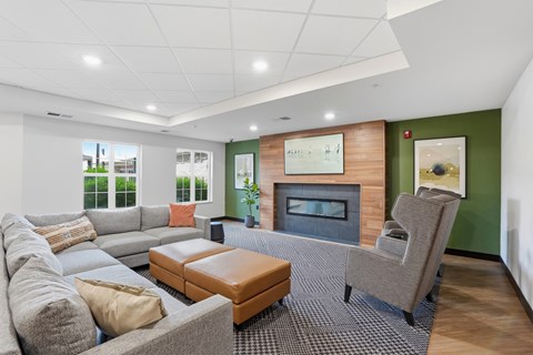 A living room with a grey couch, a brown ottoman, and a grey chair.