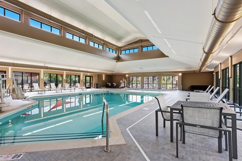 A large indoor swimming pool with lounge chairs and a metal pole.