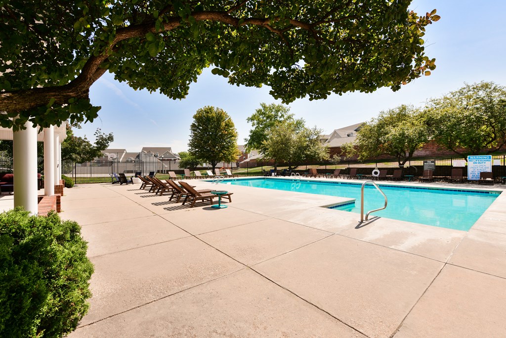 A pool surrounded by trees and chairs at The Donovan Apartment Homes, Lincoln