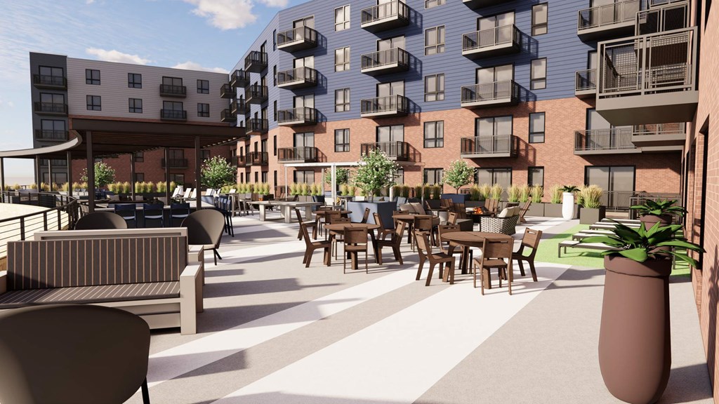 A modern outdoor seating area with tables and chairs is surrounded by apartment buildings.