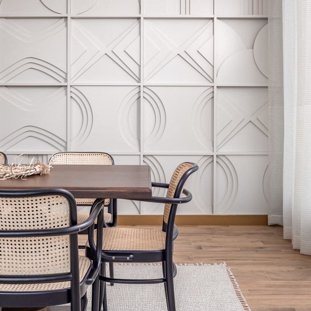 a dining area with a wooden table and rattan chairs and a white rug on the floor
