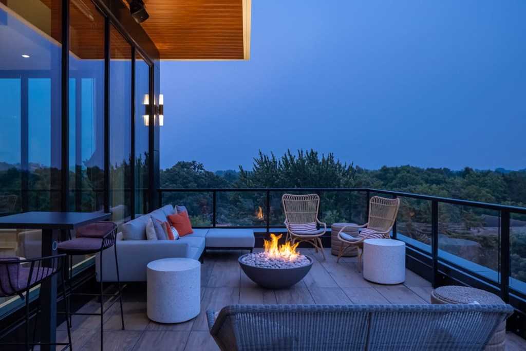 a patio with a fire pit and chairs on a balcony