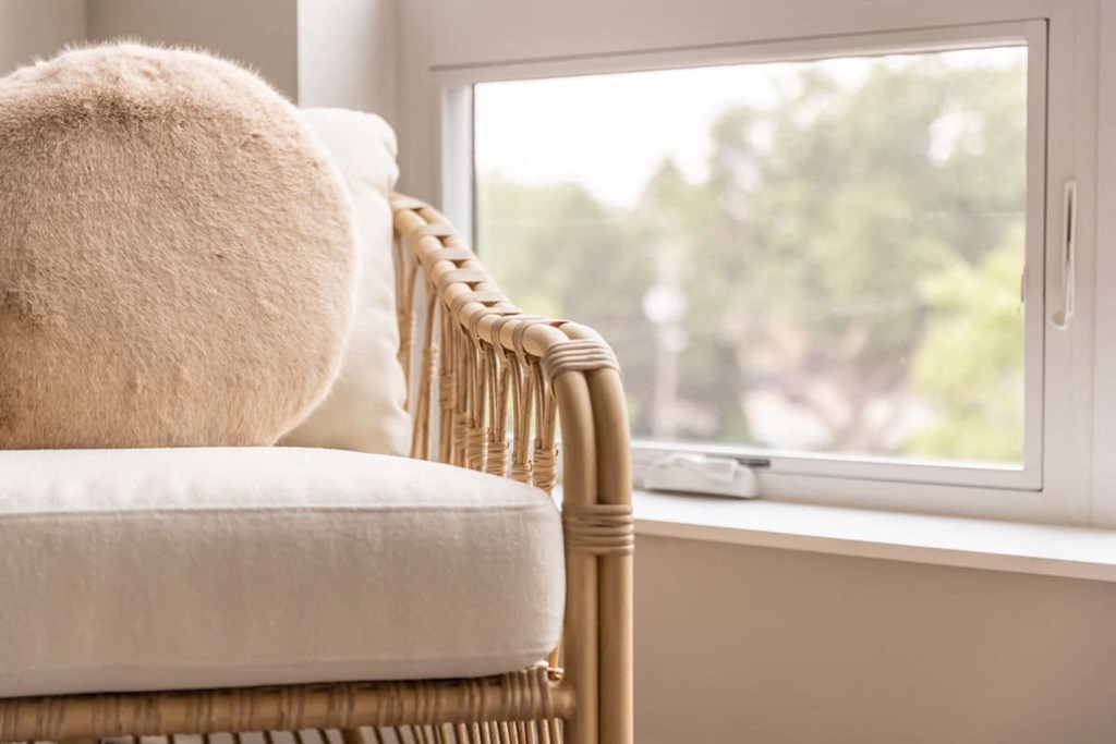a chair with a white cushion next to a window