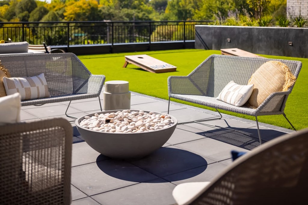a seating area with a fire pit and chairs on a patio with a lawn in the background