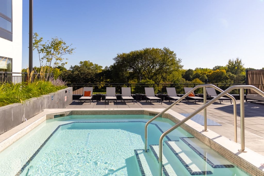 a swimming pool with chaise lounge chairs and trees in the background