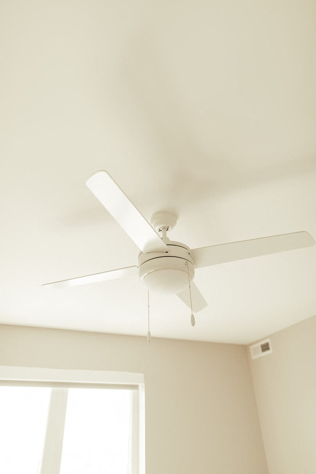 a white ceiling fan hanging from a ceiling with a window in the background