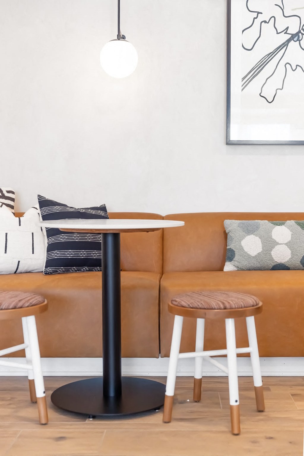 a table and two stools in front of a brown couch