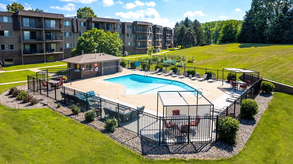 an aerial view of a resort style pool and hot tub with lounge chairs and umbrellas