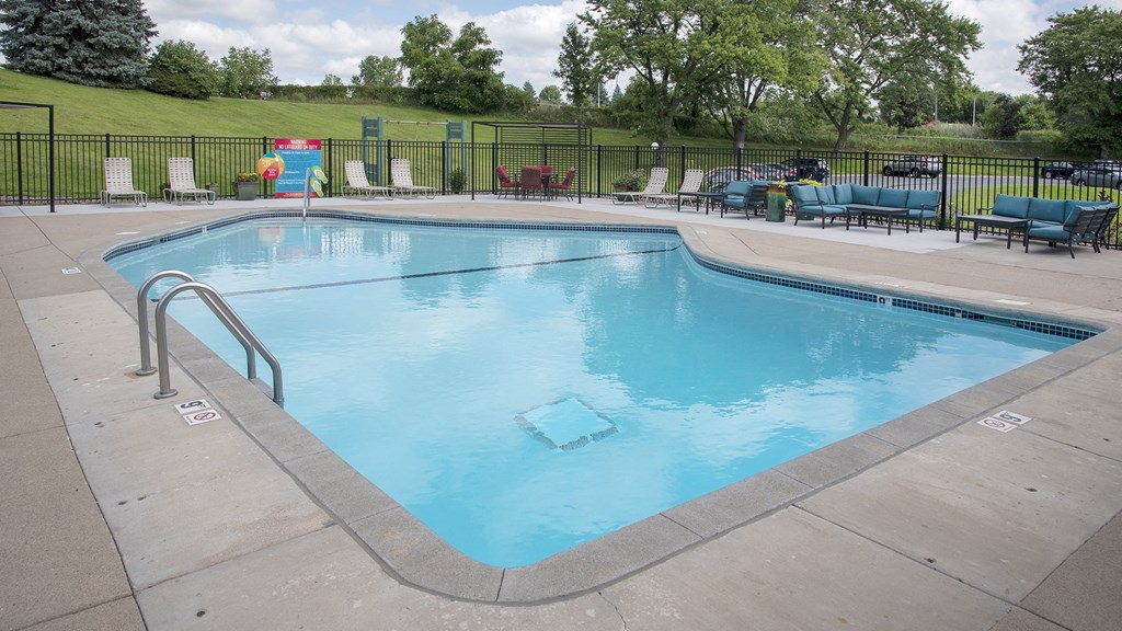 a swimming pool with chaise lounge chairs and trees in the background