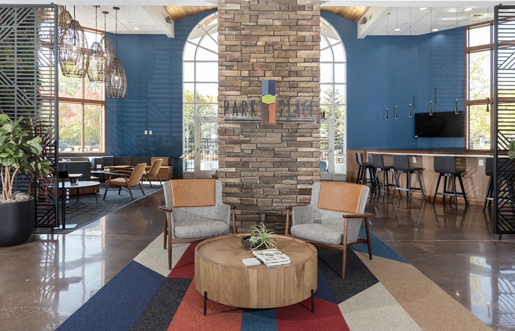 the lobby of a restaurant with a stone column and chairs and a table and a