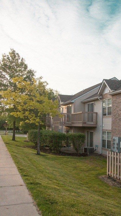 an apartment building with a yard and a sidewalk