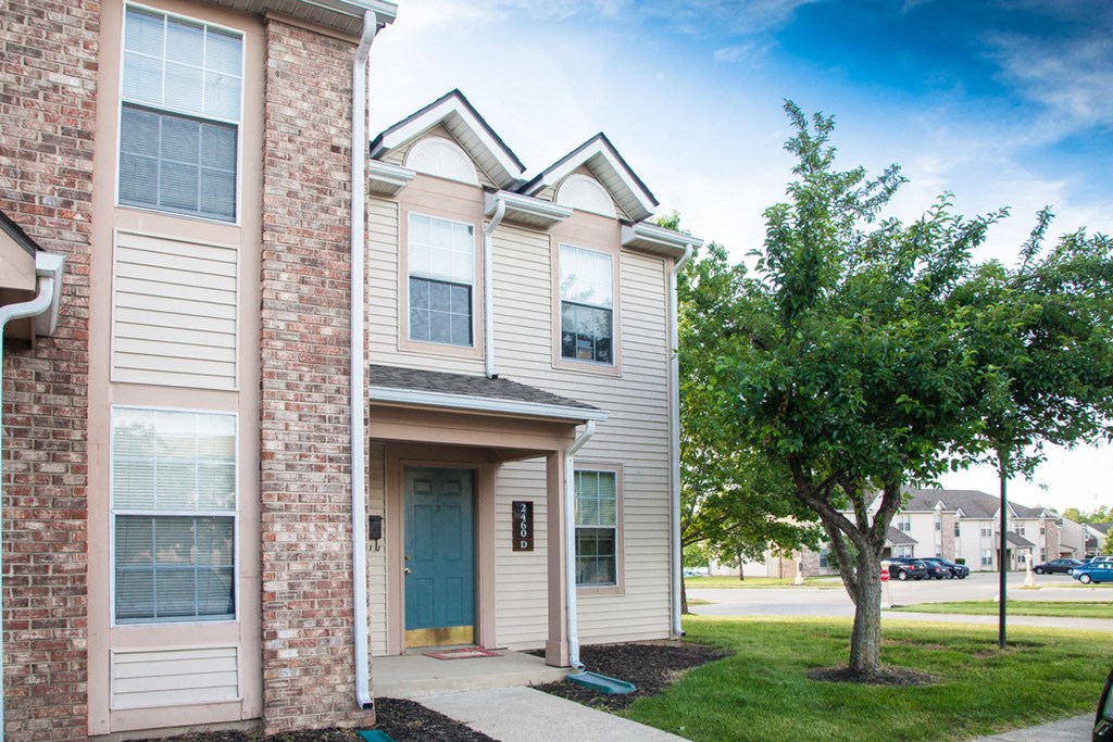 a brick apartment building with a blue door and a tree