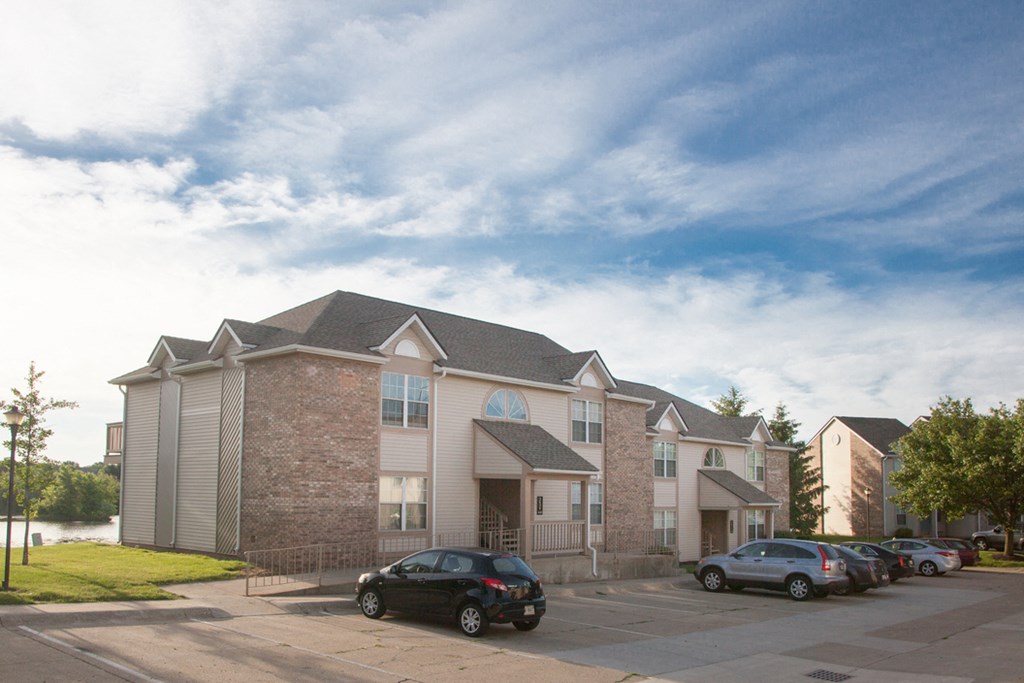 an apartment building with cars parked in a parking lot