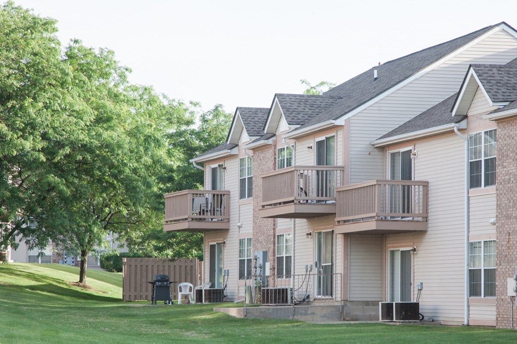 a row of houses with balconies on the side of a lawn