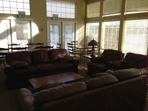 a living room with couches and a table with chairs and windows