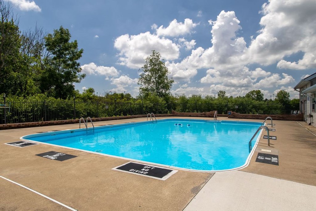 a swimming pool with trees and a cloudy sky above it