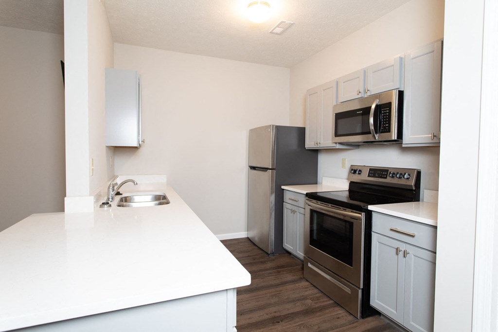 a white kitchen with stainless steel appliances and white counter tops