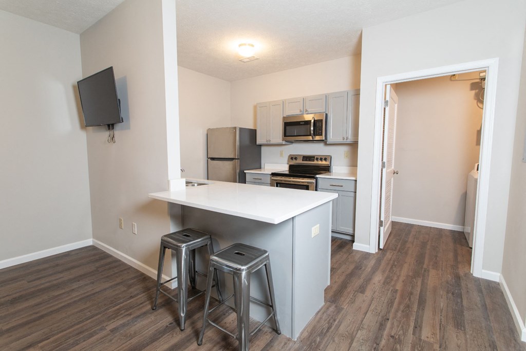a kitchen with a island and three stools in front of a counter top