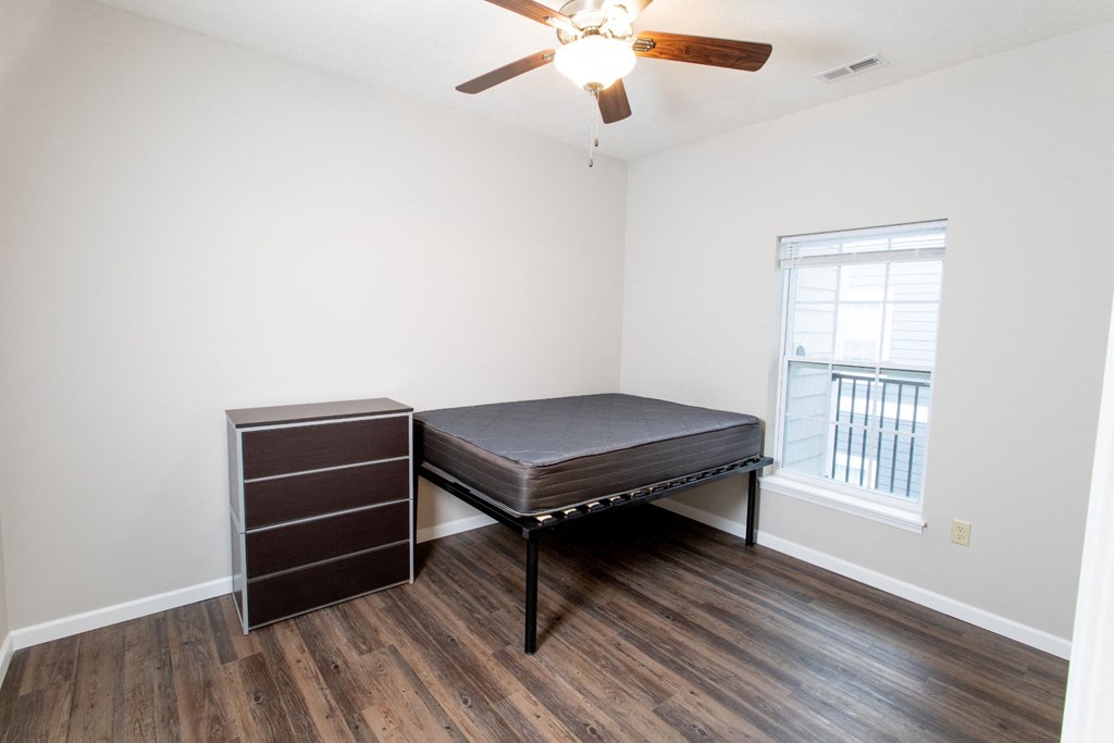 a bedroom with a bed and a dresser and a ceiling fan