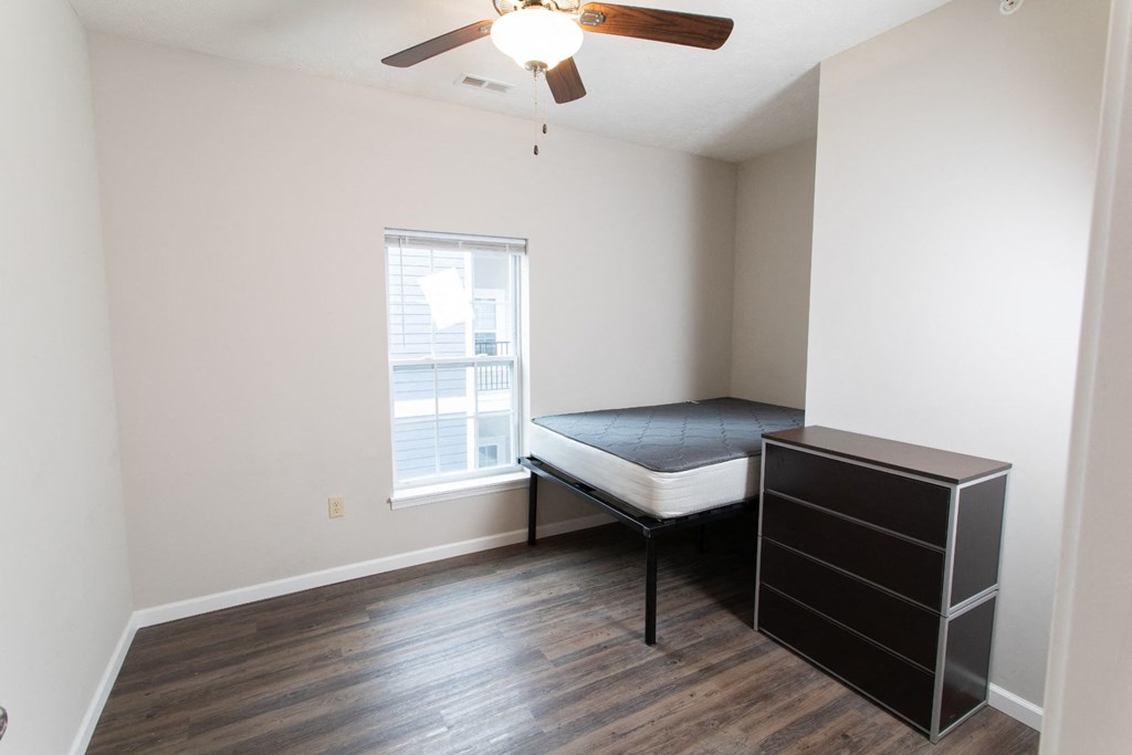 an empty room with a bed and a ceiling fan