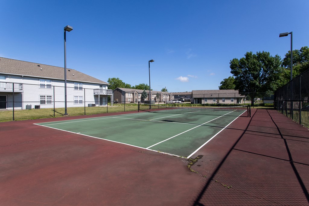 a tennis court with green and red surfaces and a building in the background