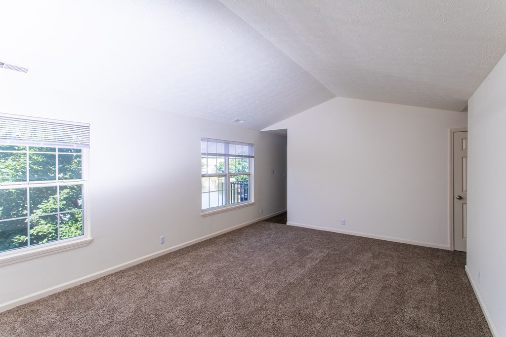 an empty bedroom with carpet and a window