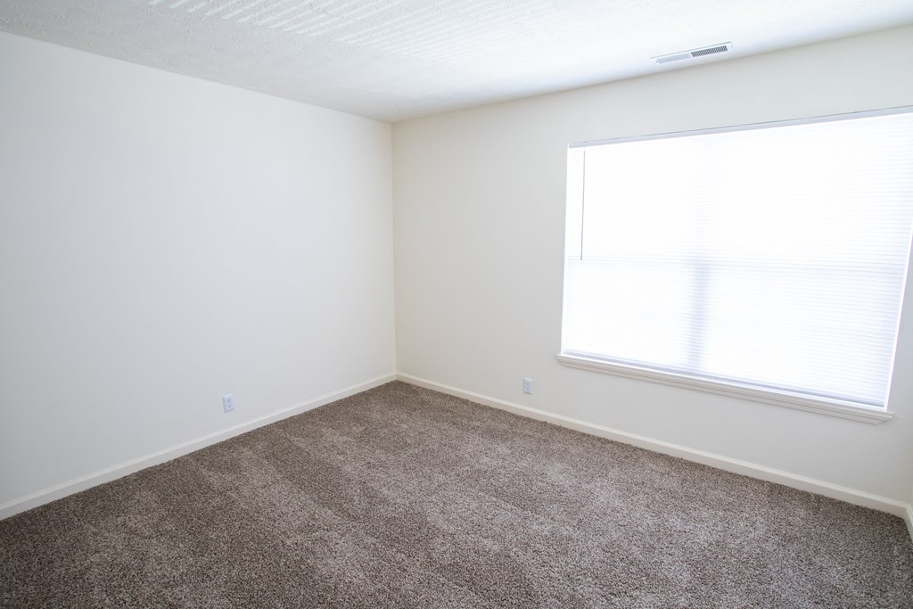 an empty room with carpet and a window