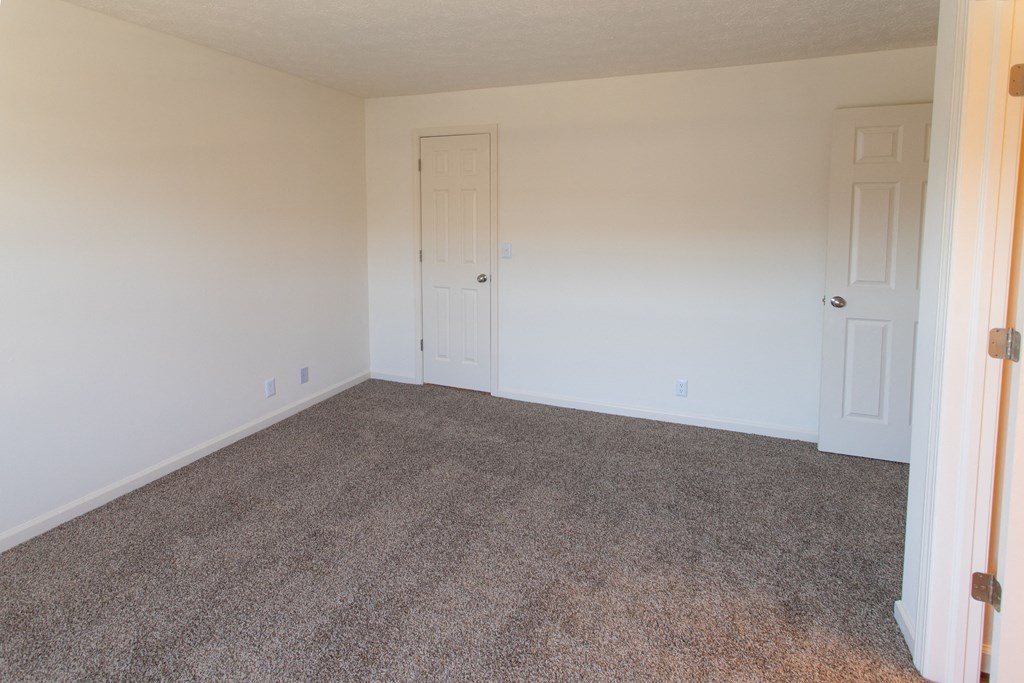 an empty room with carpet and white walls and doors