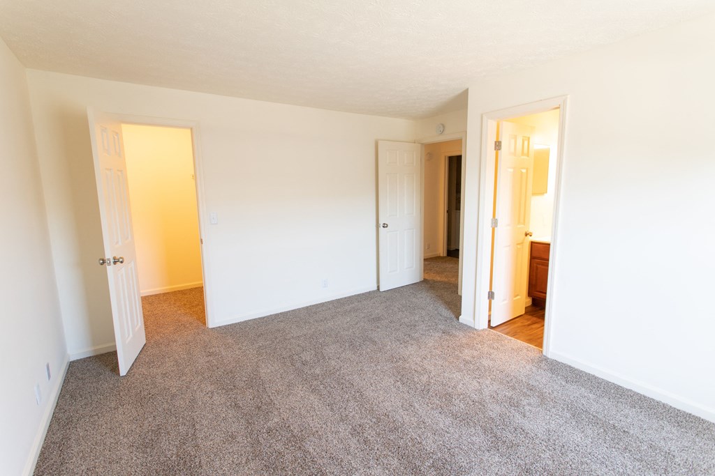 an empty living room with a carpeted floor and white walls