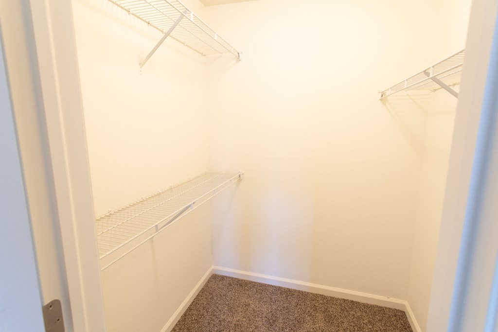 a walk in closet in a small room with white walls and shelves