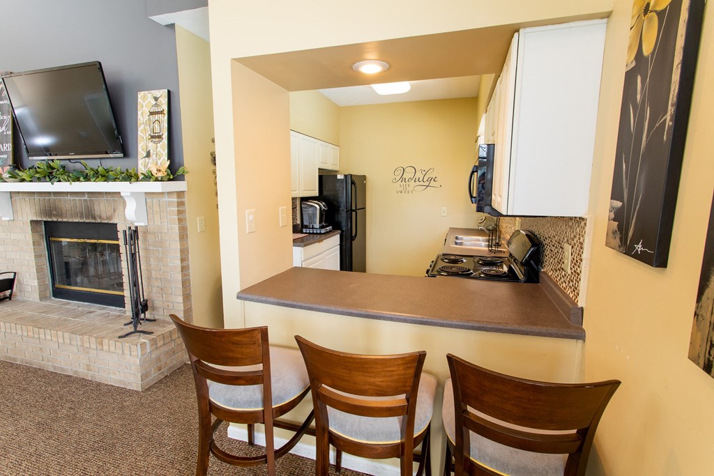 a kitchen with a fireplace and a bar with four chairs