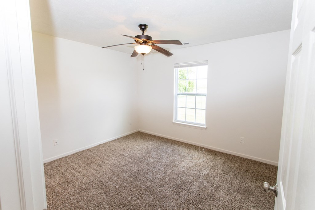 an empty room with a ceiling fan and a window