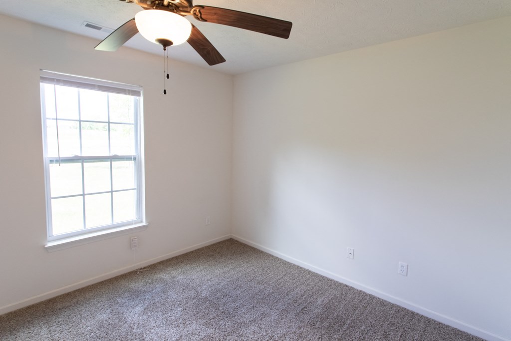 an empty room with a ceiling fan and a window