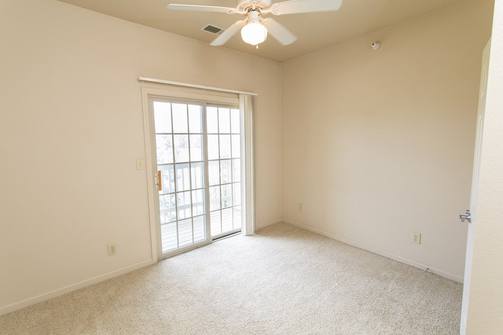 an empty living room with a ceiling fan and a window