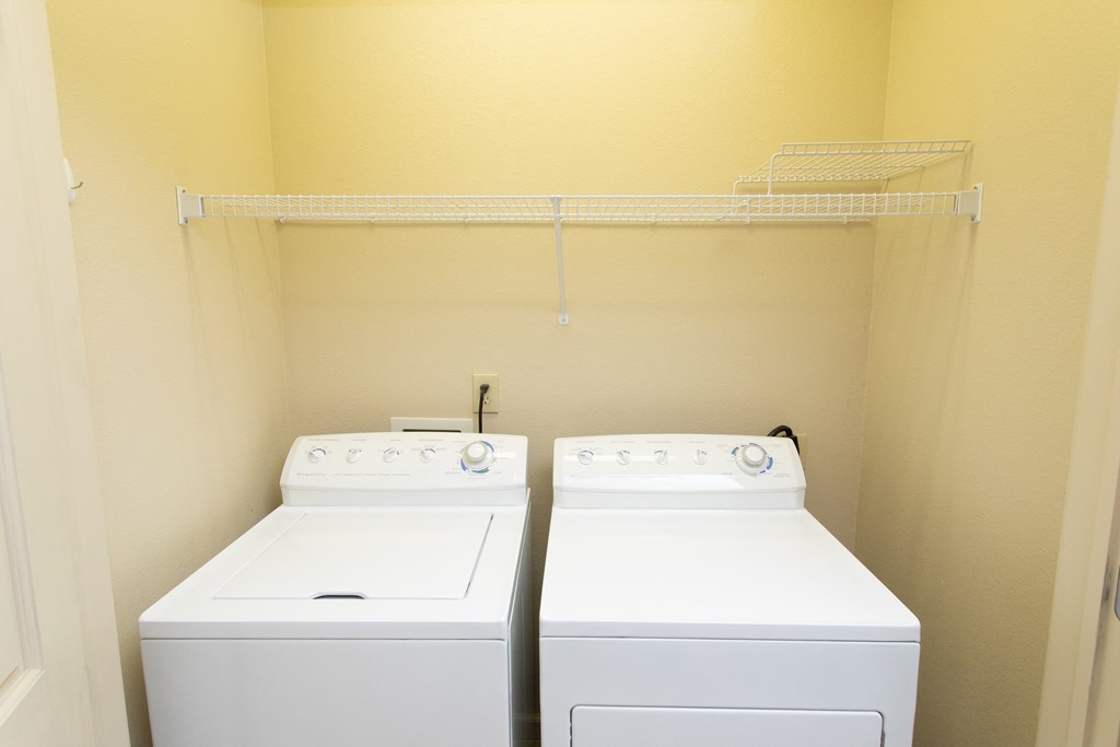 two washers and dryers in a laundry room with a shelf above
