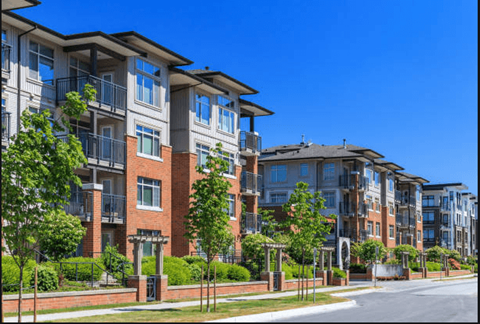 A row of modern apartment buildings with balconies and trees in front.