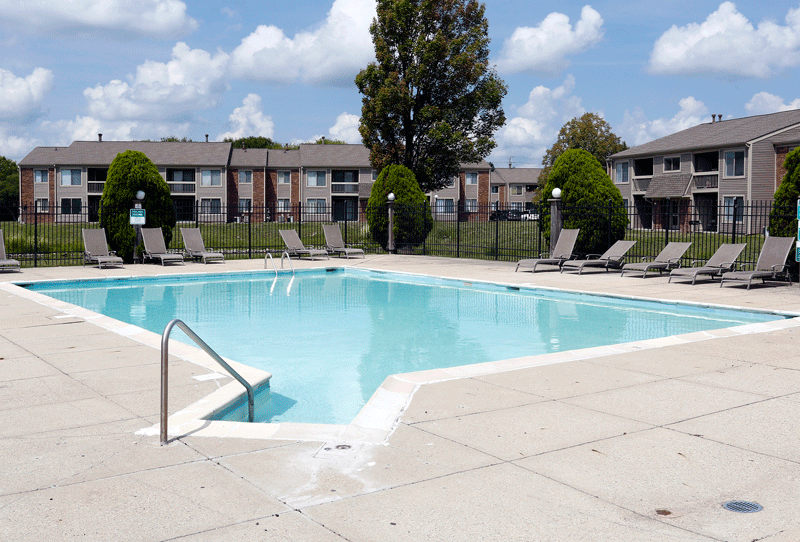 a swimming pool with chaise lounge chairs and apartment buildings in the background