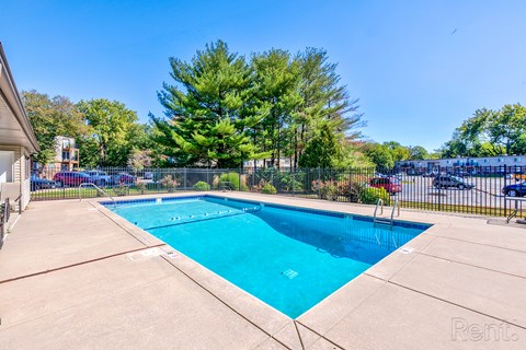 A swimming pool surrounded by a fence and trees.