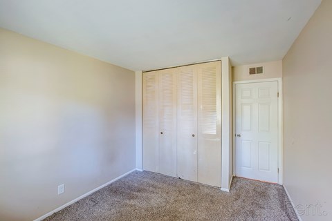 A bedroom with a carpeted floor and a white door.