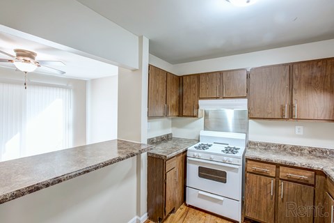 A kitchen with a stove top oven and wooden cabinets.
