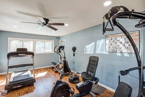 A home gym with a treadmill, exercise bike, and other equipment.