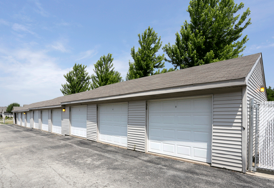 a row of garages with a fence and trees in the background