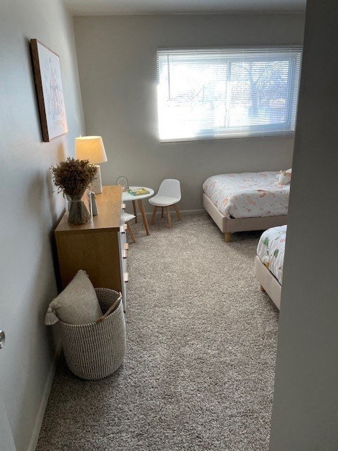 a bedroom with two beds and a table and a window