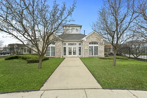 A house with a white door and windows surrounded by trees.