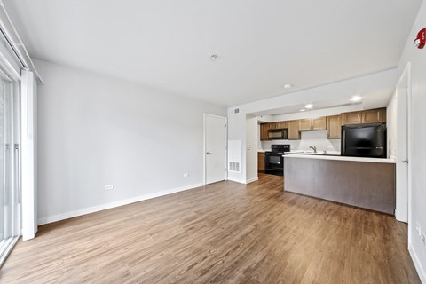 A spacious room with wooden flooring and a kitchen area with a stove and oven.