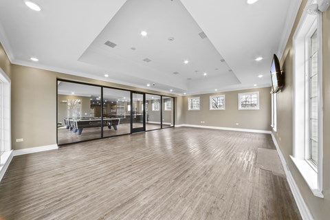 A spacious room with wooden flooring and a glass wall.