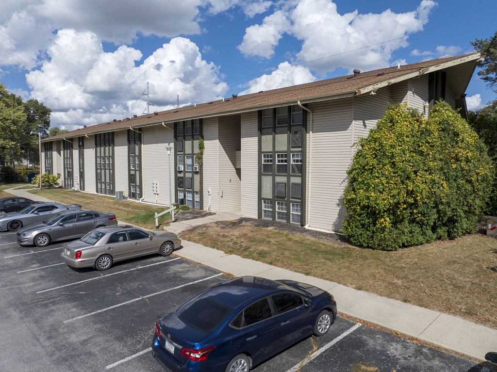 A blue car is parked in a parking lot in front of a grey building.