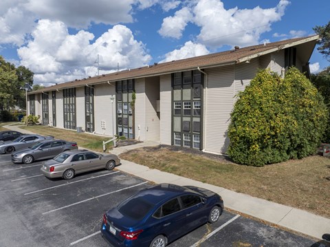 A blue car is parked in a parking lot in front of a grey building.