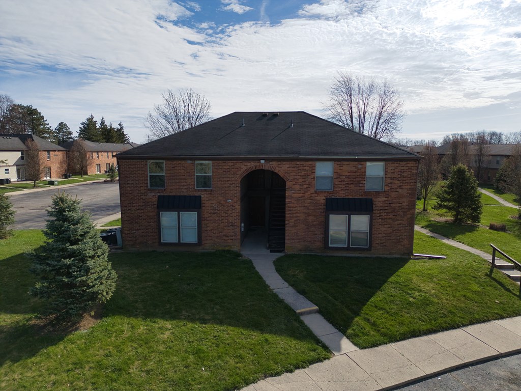 a brick building with a black roof and a sidewalk
