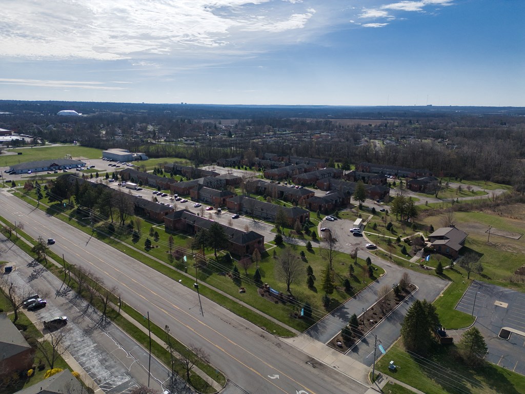 an aerial view of a neighborhood with an empty street and cars on a highway